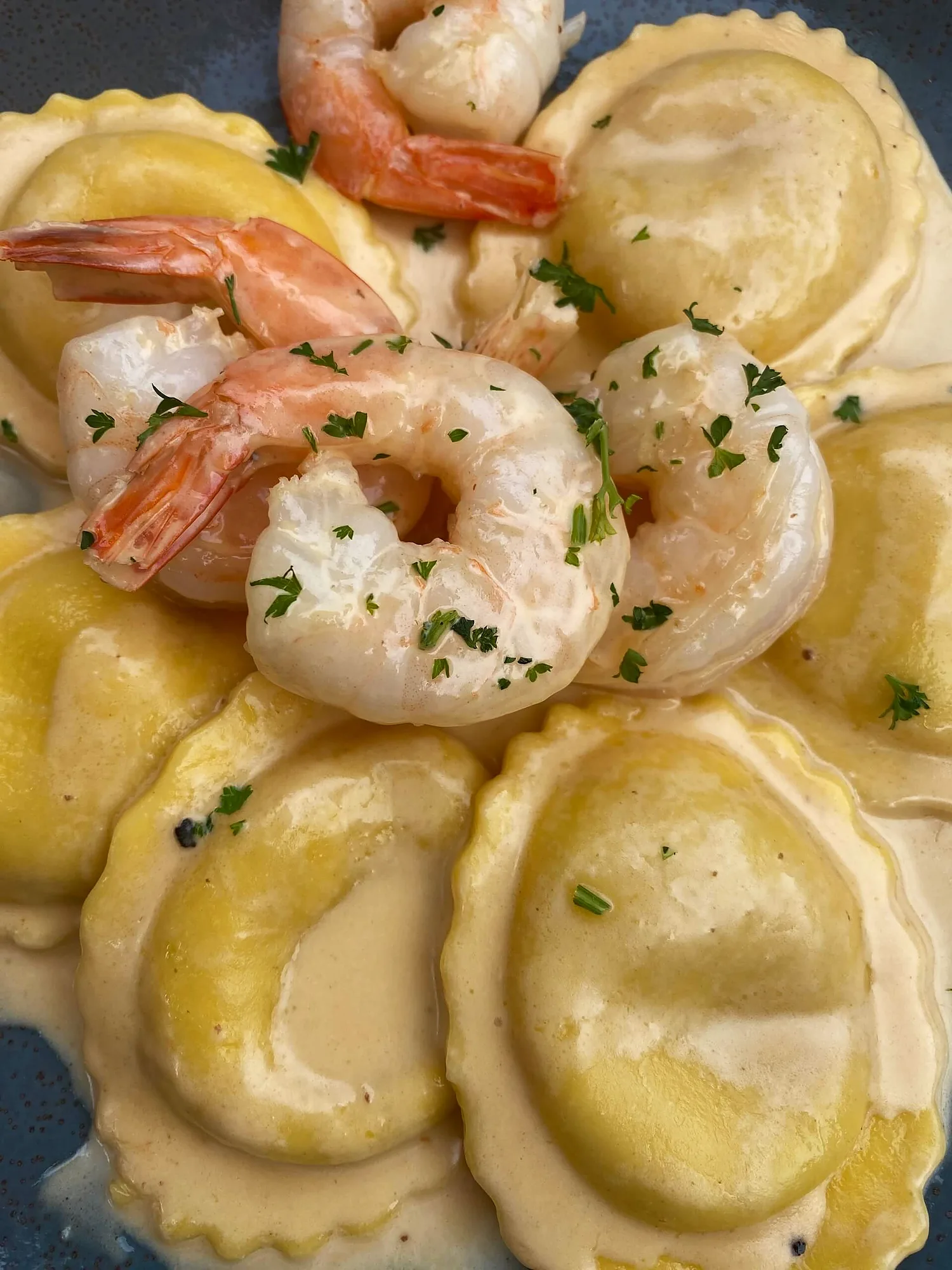 Ravioli topped with shrimp and chopped parsley in a cream sauce