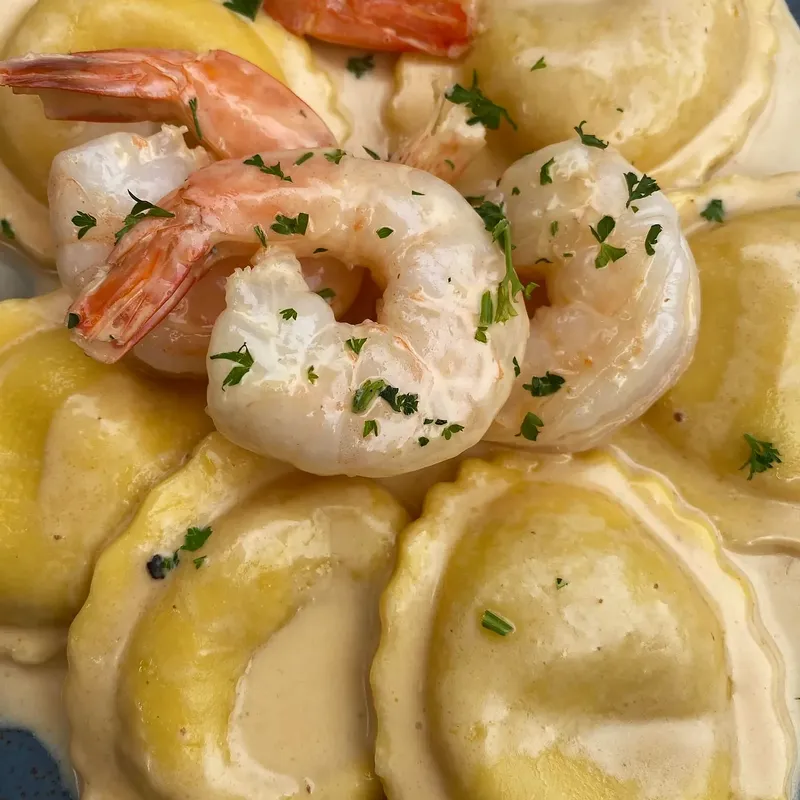 Ravioli topped with shrimp and chopped parsley in a cream sauce